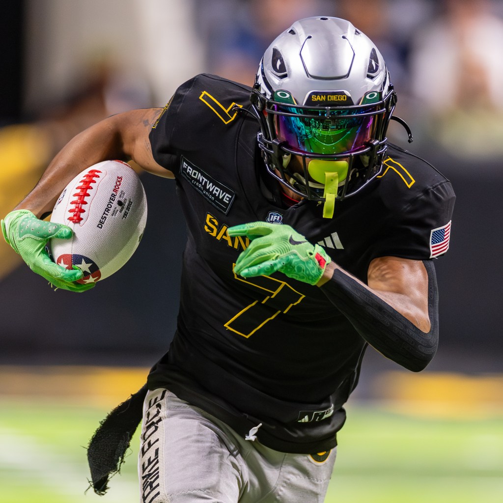 A San Diego Strike Force player in a black uniform running with a football during a game, showcasing dynamic movement and athleticism.